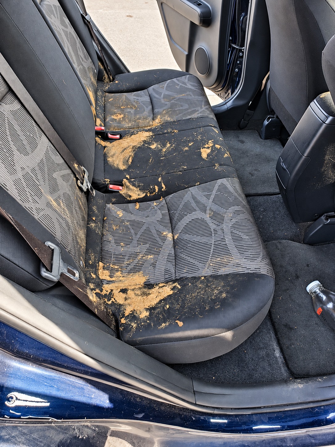 Dark patterned rear seats with visible spills before detailing